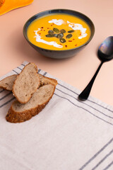 Creamy pumpkin soup served in deep bowl, topped with a swirl of cream and garnished with fresh herbs. A comforting, hearty dish perfect for autumn evenings, blending smooth textures and rich flavors.