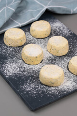 Frozen syrniki (cottage cheese pancakes) flavored with creamy cheese and dill on a dark black background, semi-finished and ready for cooking. 