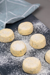 Frozen syrniki (cottage cheese pancakes) flavored with creamy cheese and dill on a dark black background, semi-finished and ready for cooking. 