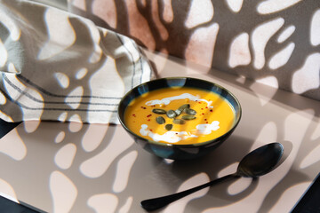 Creamy pumpkin soup served in deep bowl, topped with a swirl of cream and garnished with fresh herbs. A comforting, hearty dish perfect for autumn evenings, blending smooth textures and rich flavors.