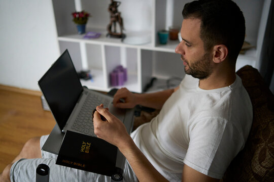 a 30-year-old man with a Bible attends an online church service, talks with the pastor