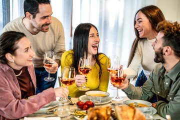 Group of smiling friends toasting red wine at dinner at home - Happy family having dining party together bar restaurant - Lifestyle concept with guys and girls eating meal and drinking