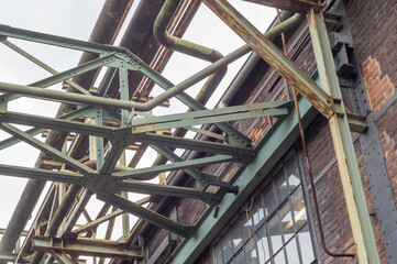 Industrial pipelines and metal framework supporting an old brick wall building