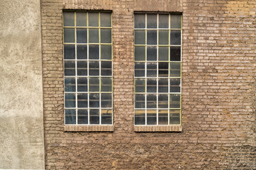 Two industrial windows illuminating old brick wall
