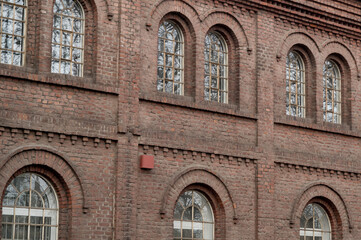 Obraz premium Arched windows illuminating red brick industrial building facade