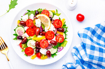 Mediterranean salad with vegetables, olives, cheese and lettuce, white background, top view