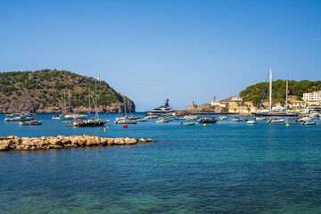 Obraz premium Beautiful coastal view tourist town of Port de Soller. Moored yachts, ships in harbor. Rocky coast, lighthouse. Mallorca, Spain. Balearic Islands