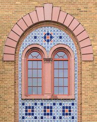 Two decorative windows surrounded by mosaic tiles under arch