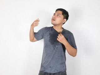 Asian man sweating while wiping sweat from his forehead with a face that looks uncomfortable