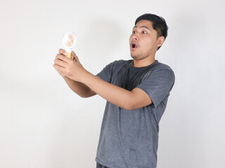 asian man sweating while using portable mini fan