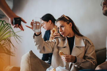 Three students gather together during a school break, enjoying a light breakfast and engaging in casual conversation, creating a relaxed and friendly atmosphere.