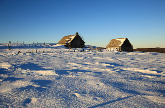 Burons sur les plateaux enneig&eacute;s de l'Aubrac au coucher de soleil.