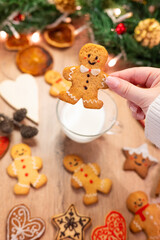 Fototapeta premium young woman holds a gingerbread man over a wooden christmas background with cookies and decorations