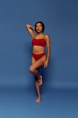 Fototapeta premium A stunning young Black woman with brunette hair exudes fashion and confidence in a studio.