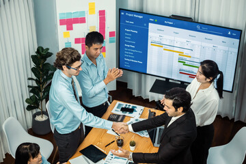 Cheerful meeting room, businesspeople celebrate with handshaking. Successful project was completed...