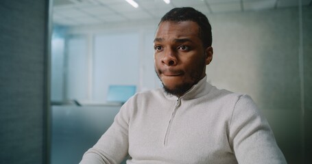 African American man works in advanced office: Successful marketing specialist or customer manager types on keyboard, chats with client or business partner about deal using PC. E-business. Rack Focus.