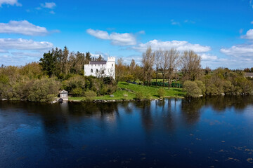 Small white fortified castle overlooks calm lake. Cargin Castle, Galway, Ireland