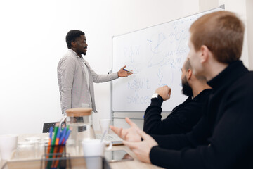 African american professional presenting project strategy to colleagues in modern office using...