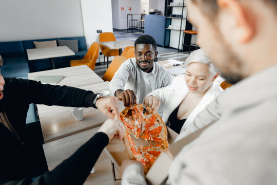 Multiracial Team Sharing Pizza in Modern Office Setting