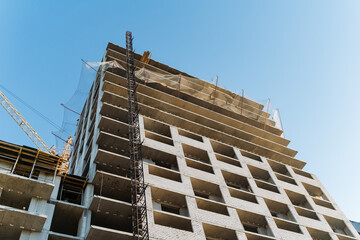 Fototapeta premium A large and impressive building is currently being constructed, with a beautiful blue sky serving as the backdrop, creating a striking contrast against the ongoing construction work
