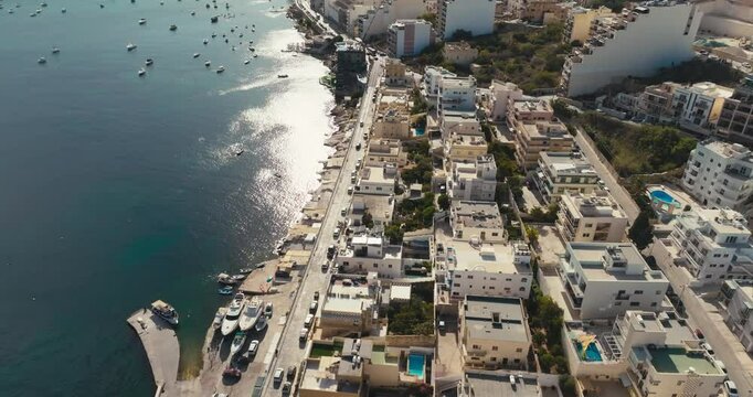 Aerial View of Bugibba in Malta Featuring Urban Seaside Landscape of the Mediterranean Shore with Tourist Beaches and Marina with Yachts and Boats. High quality 4k footage