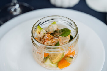 A jar that is filled to the brim with various vegetables and chunks of meat is placed carefully on...