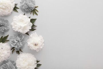 Fresh soft white and dark gray peony flowers with leaves on light gray table background. Empty place for emotional, sentimental text, quote or sayings. Closeup. Top down view.