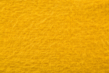 Bright yellow soft hairy knitted fabric pattern background. Closeup. Empty place for text. Top down view.