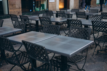 Modern outdoor terrace with seating arrangement. Fashionable outdoor restaurant tables, summer time. Tables and chairs at sidewalk cafe. Touristic setting, cafe table, sidewalk cafe furniture