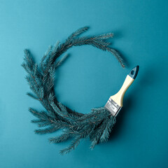 Creative Christmas wreath made of fir branches and a paintbrush on a turquoise background....