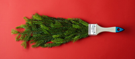 Creative Christmas banner featuring a paintbrush covered in pine branches on a red background. Ideal for festive promotions and holiday campaigns.
