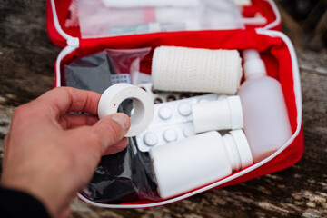 A person is holding a bandage in front of a first aid kit, indicating a readiness to provide...