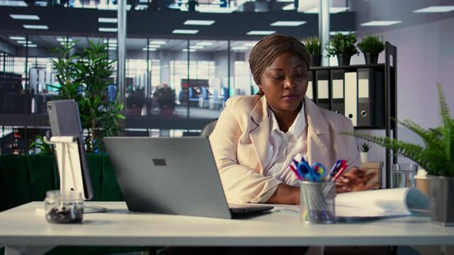 African american businesswoman demonstrating her leadership skills, working on monthly balance revenue for company growth. Leader setting a powerful example in the corporate environment. Camera B.