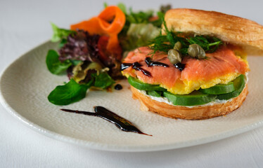 new york roll sandwich with croissant dough, smoked salmon, avocado, scrambled eggs or omelette styled with fresh greens