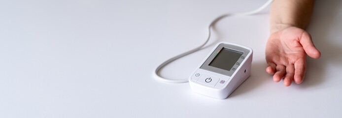 Digital Blood Pressure Monitor Device with Cuff on White Background for Health Monitoring
