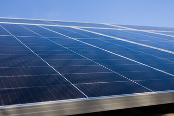 Close-up view of solar panels under a bright blue sky. Clean energy, sustainability concept.