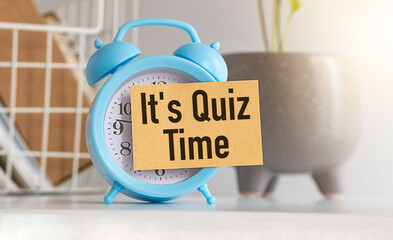 Blue Alarm Clock With Text It's Quiz Time on Office Desk