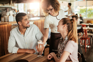Young waitress delivering coffee to a young couple in a cafe
