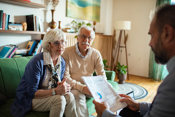Senior couple having a serious conversation with financial advisor in living room