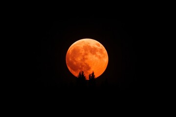 Supermoon rising above the horizon, illuminating the night sky with orange light