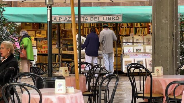 Lucca, Italy - November 27, 2024: Picturesque outdoor book market and cozy cafe scene in the historic center of Lucca. Captures the authentic Italian lifestyle, perfect for tourists and book lovers.