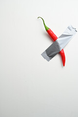 Red Chili Pepper Taped to Wall. A vibrant red chili pepper secured to a white wall with duct tape,...
