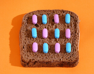 Bread with medical drugs isolated on orange background with a stiletto shadow.
