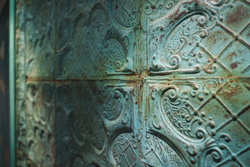 Intricately designed wall with ornate patterns and weathered turquoise patina, showcasing...