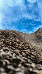 Close-up of a rugged rocky surface leading towards a bright blue sky, showcasing texture and depth.