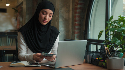 Islamic muslim Arabian ethnic woman in hijab happy girl rich wealthy businesswoman business lady female employee financial accountant count money cash finance budget satisfied gain salary in office