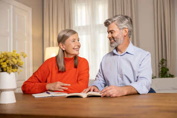 Mature couple sitting at the table and making notes together