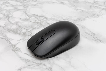 Black computer mouse is sitting on a white marble countertop
