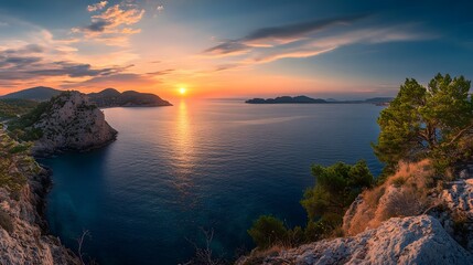 Fototapeta premium Sunset over the ocean, painting the sky with vibrant oranges and pinks. A tranquil scene with rocky cliffs and lush greenery.