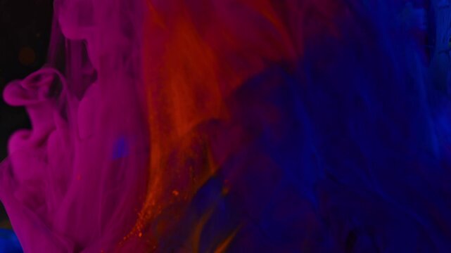 Abstract background. Blue and orange inks flow and mix into the orange ink trail in water.